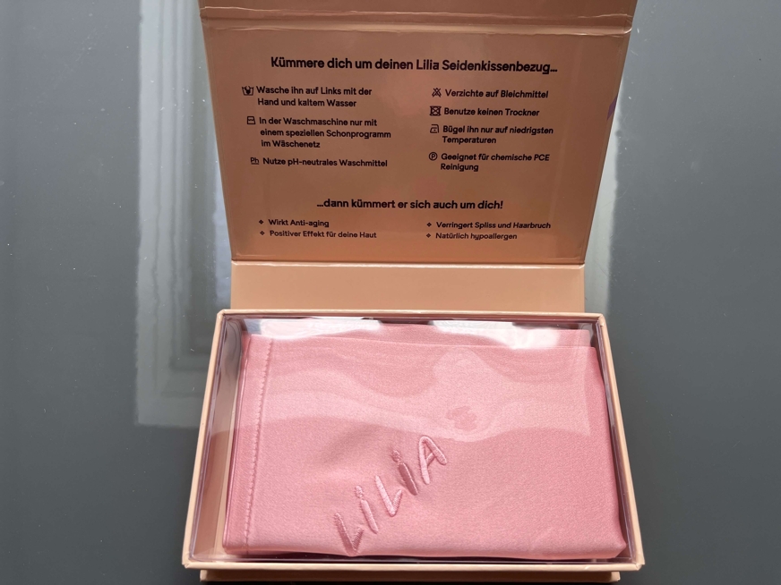 Caixa de cartão com fronha de seda rosa dobrada no interior